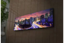 Lerretsbilde med LED-belysning 30x90 cm - Bysilhuett i skumringen med lysstråler fra veiene